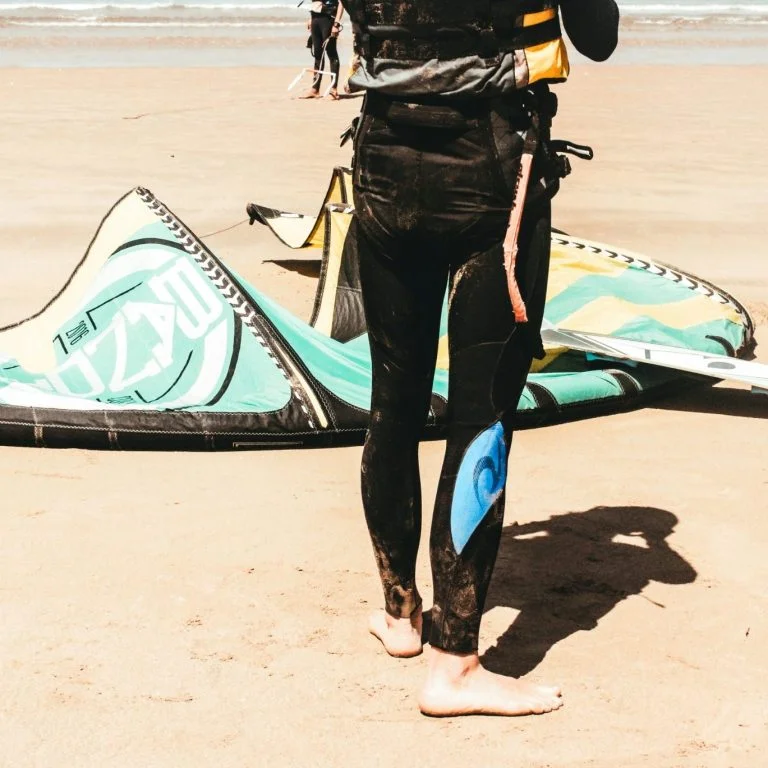 Wassersportler mit Kiteausrüstung am Strand